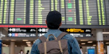Viajero mira el panel de información de un aeropuerto