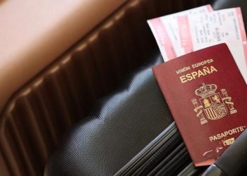 Un pasaporte español encima de unas maletas