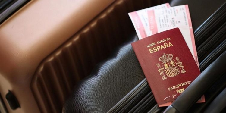 Un pasaporte español encima de unas maletas